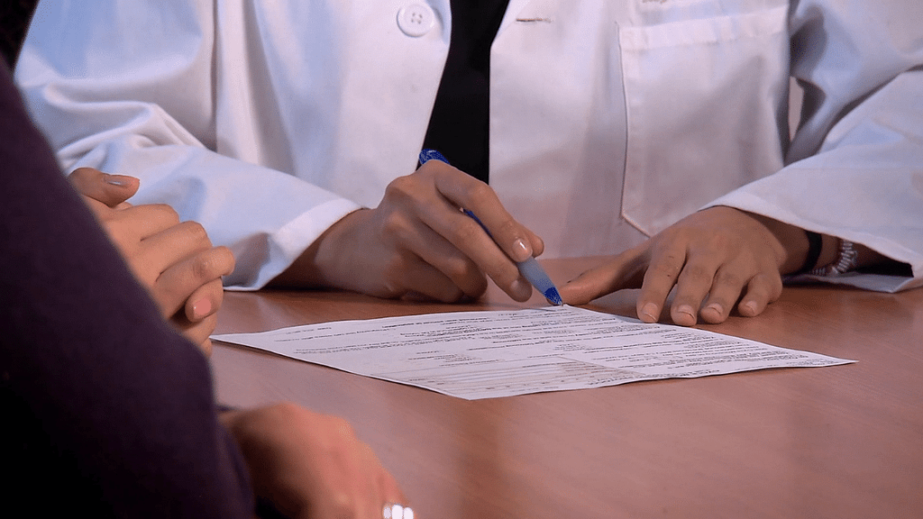Photograph of doctor's hands writing on paper with pen