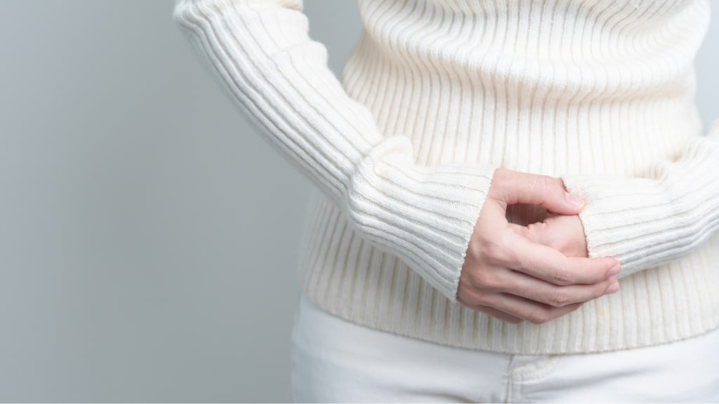 person holding stomach, dressed all in white