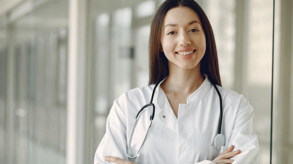 Crop doctor in medical uniform with stethoscope standing in clinic corridor