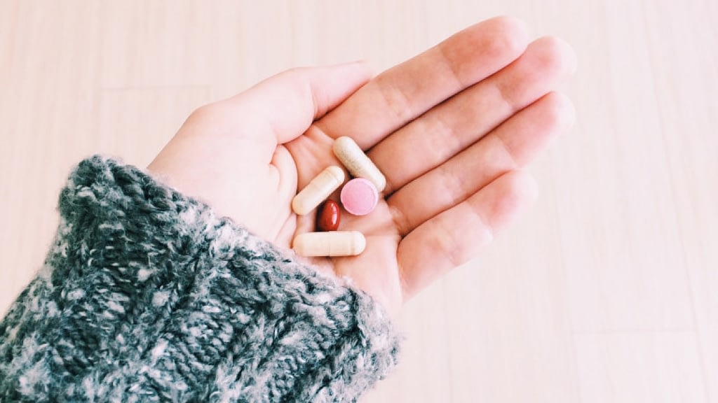 A photograph of a hand holding vitamins.