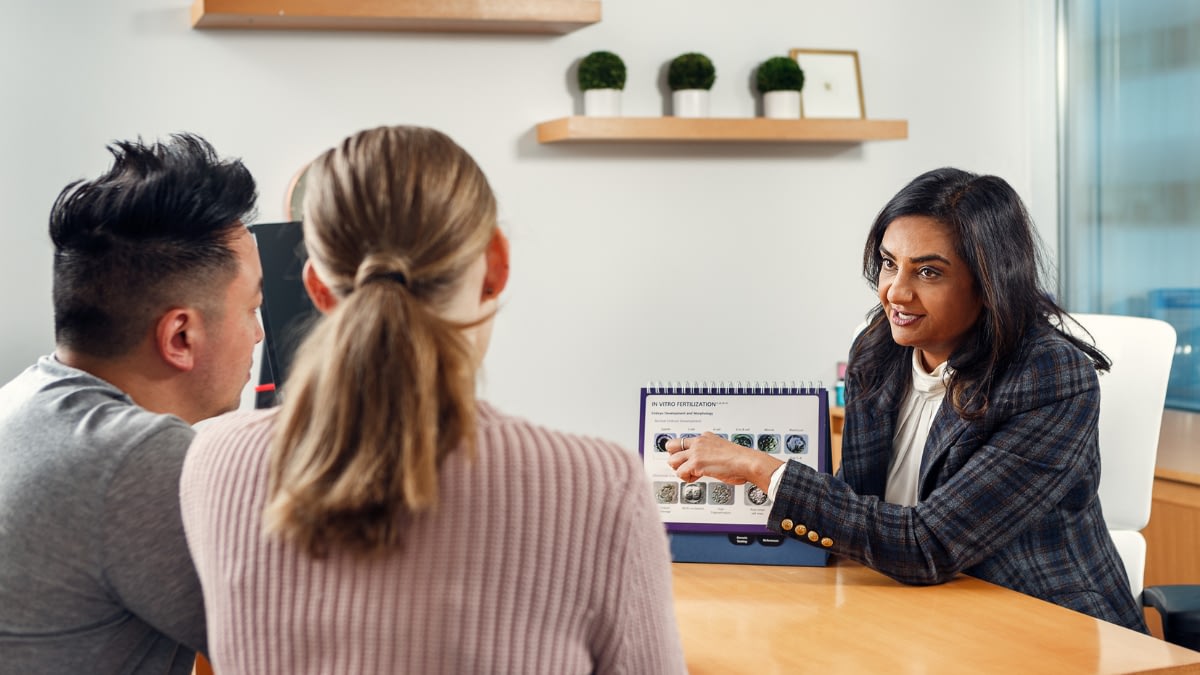 Photo of Dr. Sierra with a couple at a desk having fertility consultation