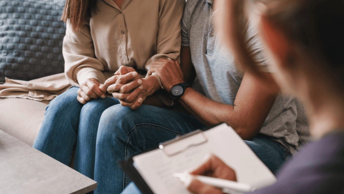 couple holding hands with doctor writing notes