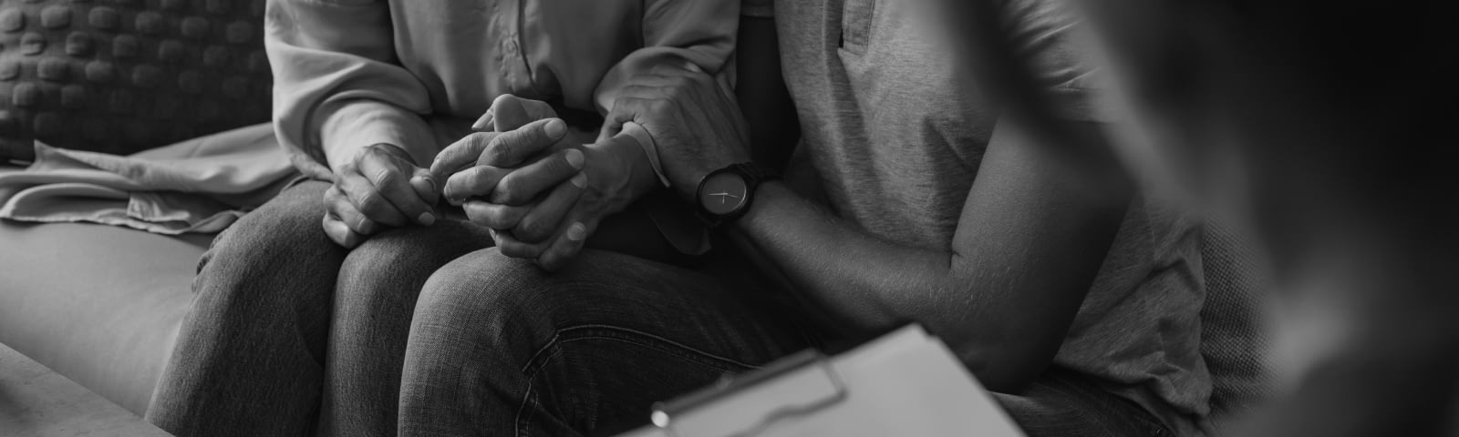 A photograph of two people sitting and holding hands.