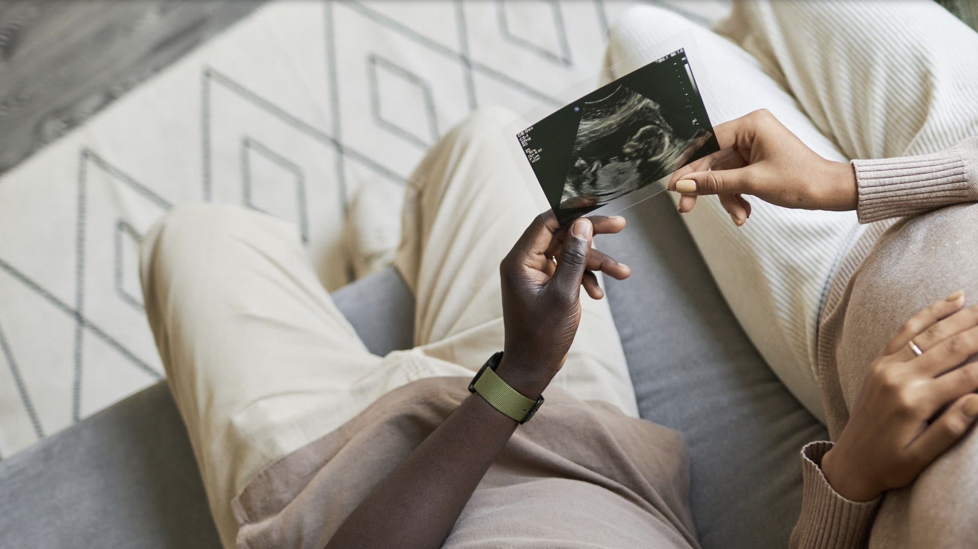 Couple sitting together holding an ultrasound photo of their baby.