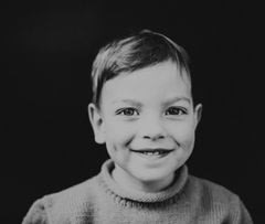 Black and white portrait style photograph of a smiling boy
