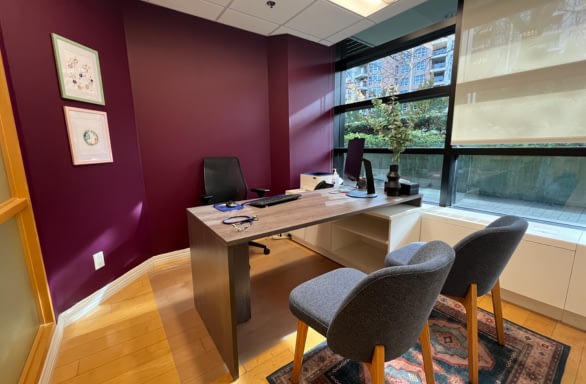 bright medical office with desk and two chairs, large window and burgundy walls.