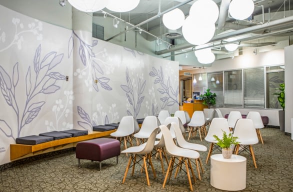 TRIO waiting room, bright, white chairs, purple and white mural on walls.