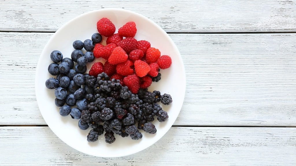 A photograph of a plate with raspberries, blackberries and blueberries.