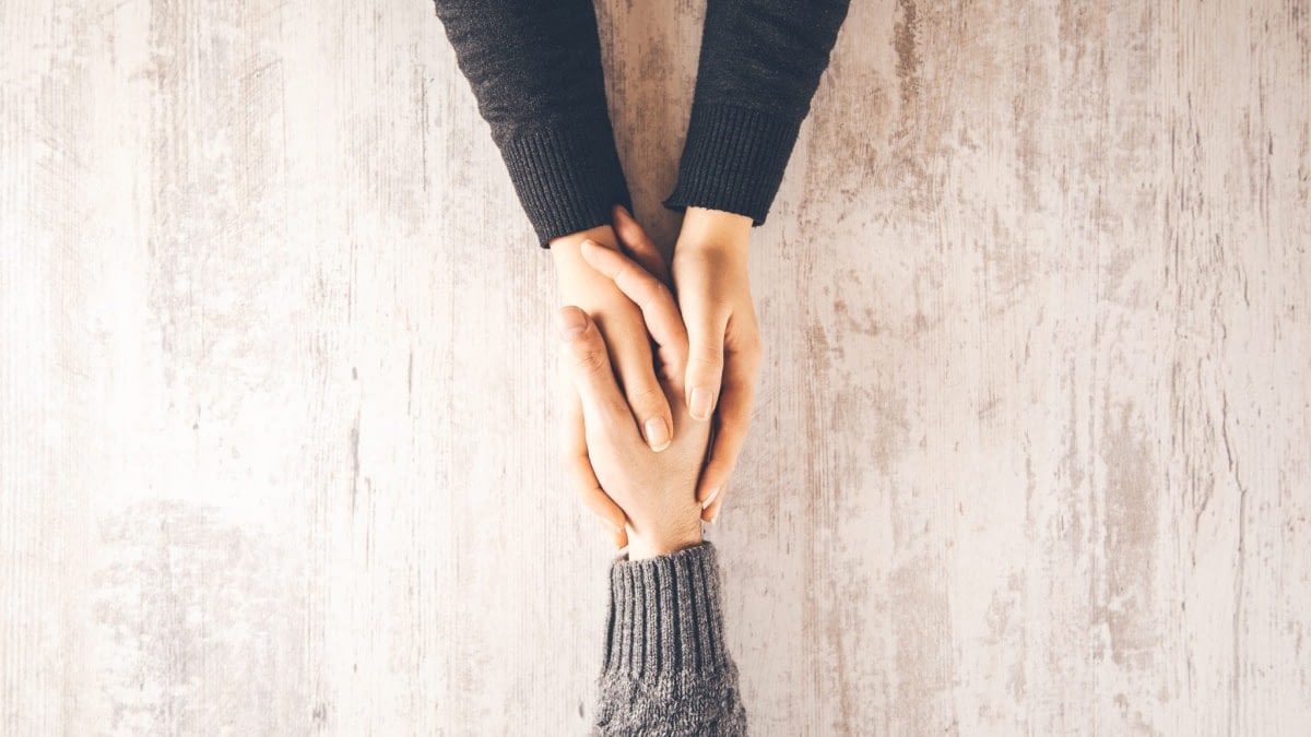 A photograph of two hands holding another hand.