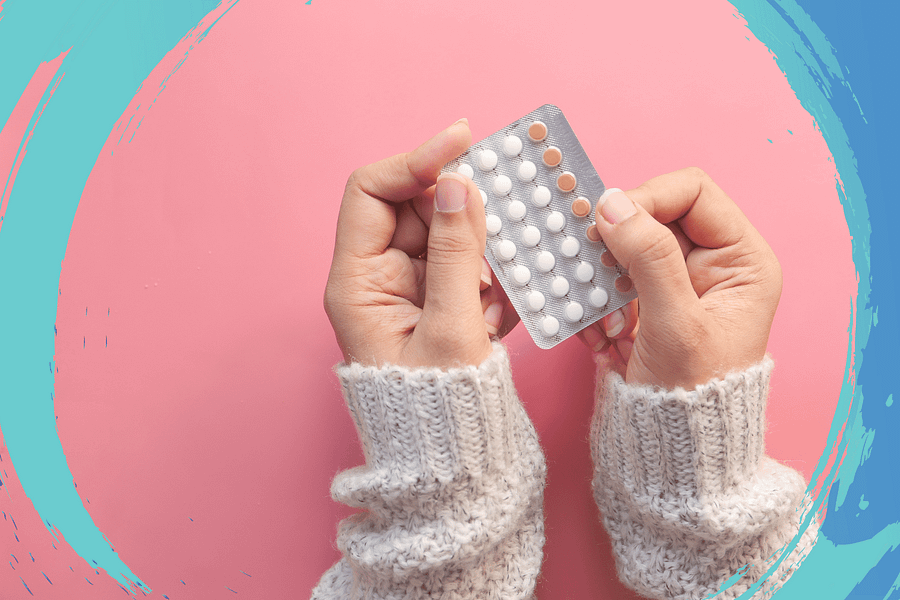 Women Hand Holding Birth Control Pills on Pink Background