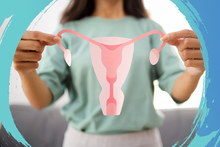 A woman holding a paper cutout depiction of a female reproductive system.